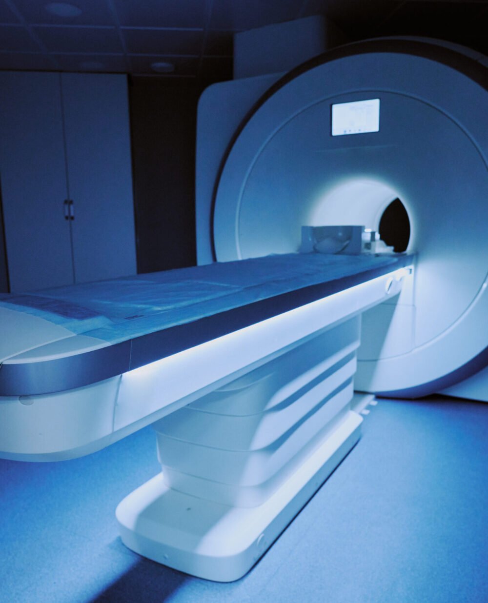 Magnetic Resonance Imaging Scanner Operating in Modern Hospital Room MRI scanner standing in hospital room with examination table extended, showing advanced medical imaging equipment used for diagnostic purposes in healthcare setting